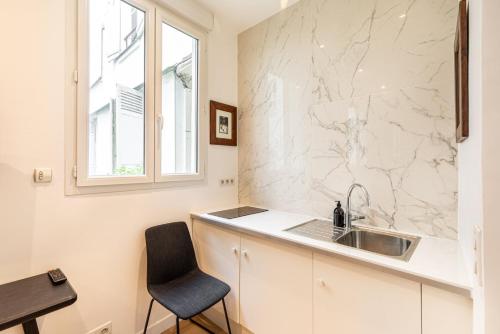une cuisine avec un évier et un comptoir avec une chaise dans l'établissement GuestReady - Élysée Palace Marble Haven, à Paris