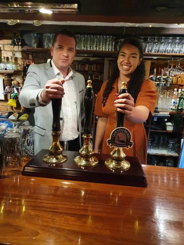 a man and a woman standing behind a bar with trophies at The Royal Arms Hotel in Sutton Cheney