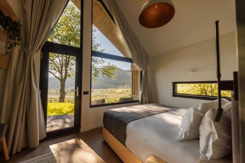 a bedroom with a large bed and large windows at Reconnect Glamping Stulpicani in Stulpicani