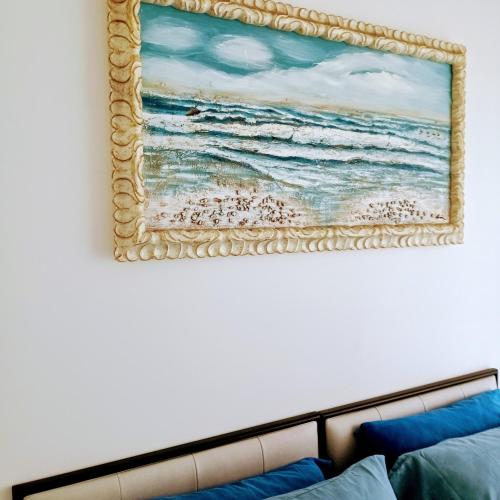 a painting of the ocean on a wall above a bed at Casa Jasmine in Camporosso