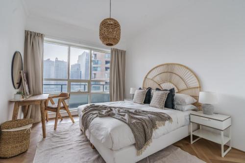 a white bedroom with a large bed and a desk at GuestReady - Bohemian Apt with Marina View in Dubai