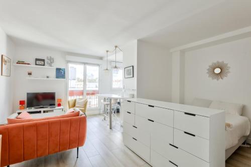 - une chambre blanche avec une commode blanche et un canapé orange dans l'établissement Bel appart à 5 min à pied de la station de métro, à Paris