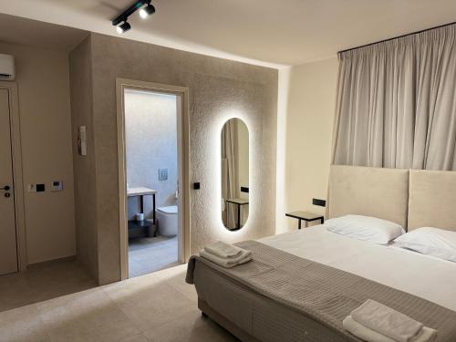 a bedroom with a bed and a bathroom with a mirror at Home of the Muses in Ayia Napa