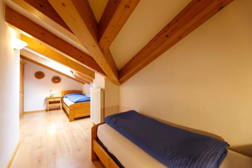 a bedroom with two beds and wooden ceilings at Residence Montebel in Tesero