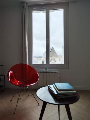 une chaise rouge et une table dans une chambre avec fenêtre dans l'établissement les Lices, à Angers