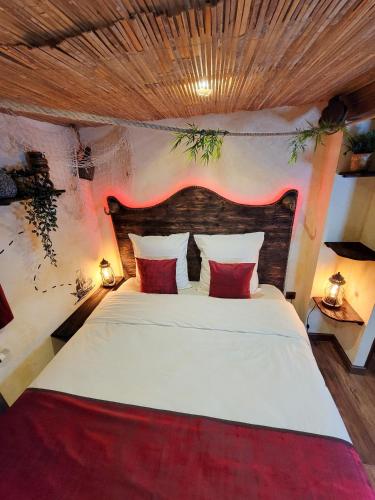 une chambre avec un grand lit blanc avec des oreillers rouges dans l'établissement Dormir Chez les Pirates charme & confort à 10 min de Colmar, à Sainte-Croix-en-Plaine