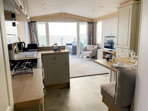 a kitchen and living room with a view of the ocean at Swift Mosselle Pitch 24 Creek Caravan Park dog friendly in Ringstead