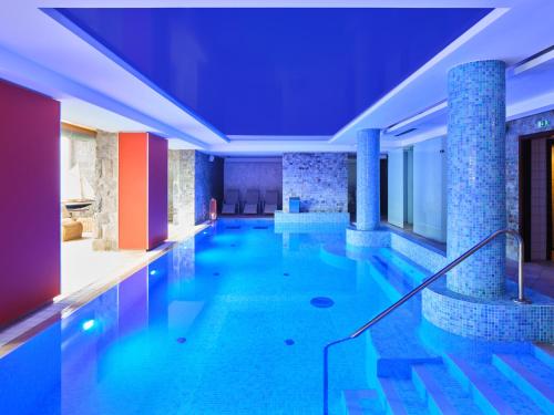 a pool with blue water in a building at Spa hotel Lanterna in Velké Karlovice