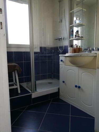 une salle de bain bleue avec une douche et un lavabo dans l'établissement Duplex face Mer au pied des plages exceptionnelle vue mer, à Arzon