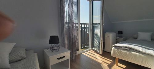 a white bedroom with a bed and a balcony at Domki Puszek in Łeba