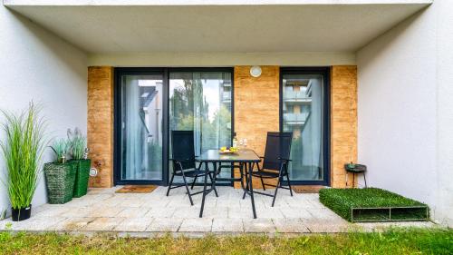 a patio with a table and chairs in front of a house at Apartamenty Piamola Jantar Park in Jantar