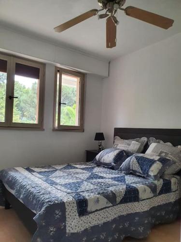 une chambre avec un lit et un ventilateur de plafond dans l'établissement le Nid Enchanté, à Cavalaire-sur-Mer