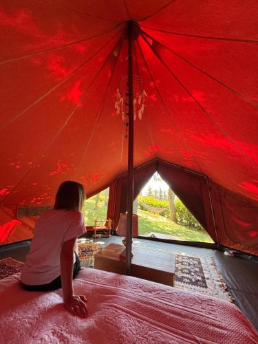 a little girl sitting on a bed in a red tent at Glamping Marche Nascoste Tenda e intero alloggio in Penna San Giovanni