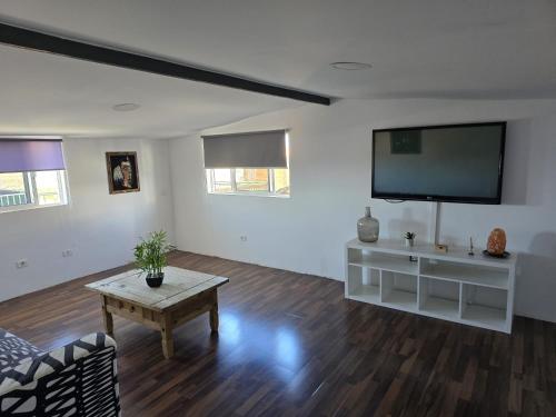 Una sala de estar con un televisor de pantalla plana y una mesa. en La Casablanca, en Pasito Blanco