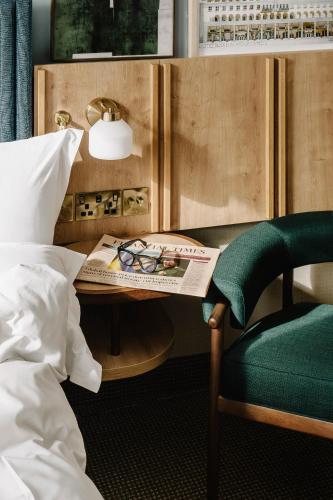 a bedroom with a bed and a table with a newspaper and a chair at Club Quarters Hotel St Paul's, London in London