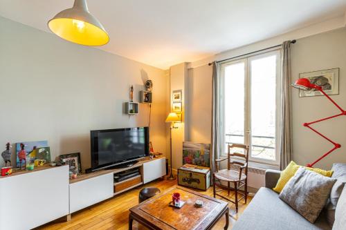 salon z kanapą i telewizorem w obiekcie GuestReady - Amazing stay in the 19th arr. w Paryżu