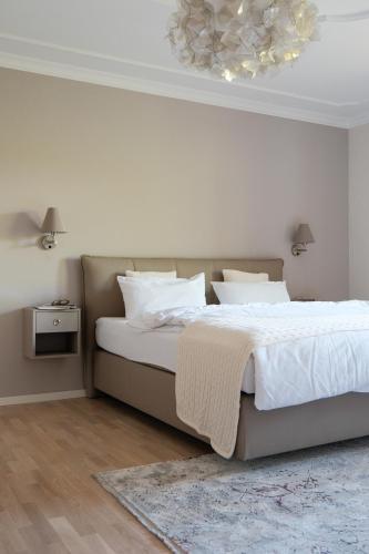a bedroom with a bed with white sheets and a chandelier at Hotel-Restaurant Kreuzberghof Tagungs- und Veranstaltungshotel in Tiefenbach