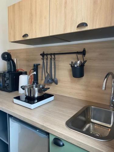 une cuisine avec un évier et un comptoir avec des ustensiles dans l'établissement Appartement cosy centre-ville Vichy, 23 m², proche thermes, à Vichy