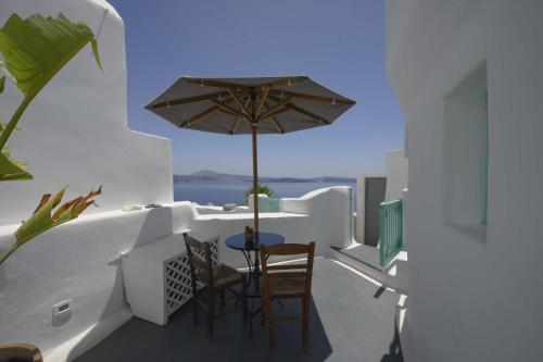 a balcony with a table and chairs and an umbrella at Sophia Oia View in Oia