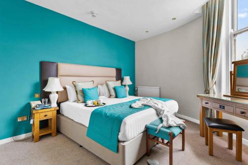a bedroom with a bed and a blue wall at The Grand Hotel in Torquay