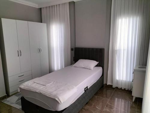 a bedroom with a bed and white cabinets and white curtains at Liz Villa in Ortaca