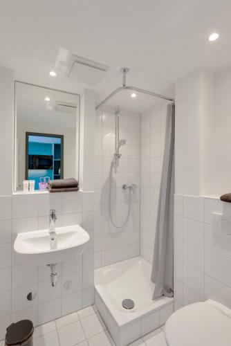 a white bathroom with a shower and a sink at MIAMI House in Hamburg