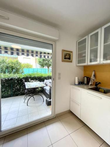 une cuisine avec vue sur une table et un balcon dans l'établissement Jolie Appartement de Bord de la Mer Côte d'Azur, à Roquebrune-Cap-Martin