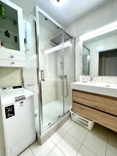 une salle de bain blanche avec une douche et un lavabo dans l'établissement Jolie Appartement de Bord de la Mer Côte d'Azur, à Roquebrune-Cap-Martin