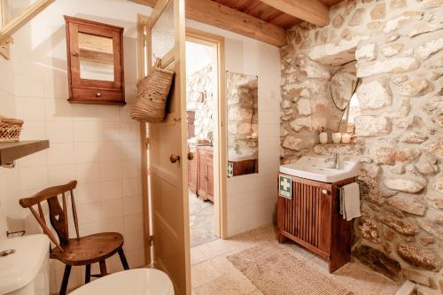 a bathroom with a stone wall and a toilet and a sink at LIKE-HOME-Kina Houses - Ericeira zone in Mafra