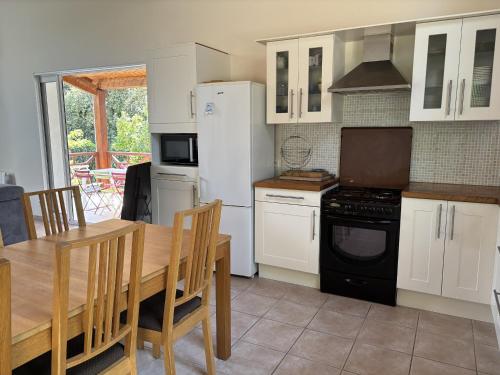 une cuisine avec des armoires blanches et une table en bois dans l'établissement L ESCIL Domino 500m de la plage by Edgar et Alfred, à Saint-Georges-dʼOléron