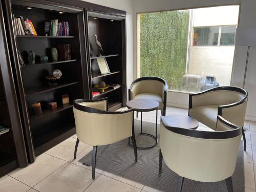 a living room with three chairs and a book shelf at Kenton Palace Bariloche in San Carlos de Bariloche