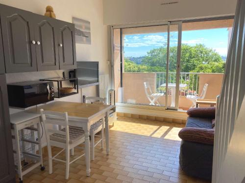 une cuisine avec une table et une vue sur un balcon dans l'établissement T1 Mezzanine à 10 min des Thermes avec Garage et Wifi - FR-1-553-187, à Balaruc-les-Bains