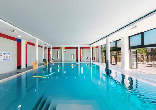 a large swimming pool with blue water in a building at Dives-sur-Mer le Conquérant in Dives-sur-Mer