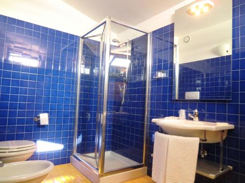 bagno piastrellato blu con doccia e lavandino di Hotel Cristoforo Colombo a Osimo