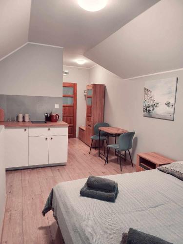 a bedroom with a bed and a kitchen with a table at Niebieska Willa in Jastarnia