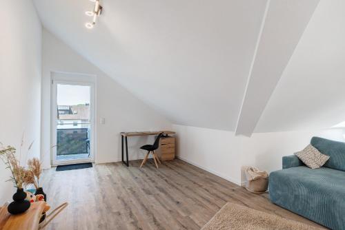 a living room with a blue couch and a desk at Neubau Ferienwohnung Kleine Auszeit in Sinzheim