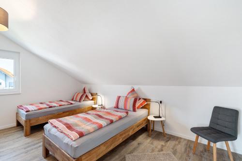 a bedroom with two beds and a chair at Neubau Ferienwohnung Kleine Auszeit in Sinzheim