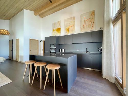 une cuisine avec un comptoir noir et des tabourets dans l'établissement Homency - Résidence Phoenix B46, à L'Alpe-d'Huez