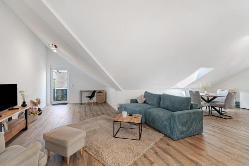 a living room with a blue couch and a table at Neubau Ferienwohnung Kleine Auszeit in Sinzheim