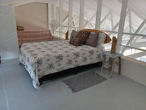 a bedroom with a bed with a blanket and a table at Galene Beach Cottage in Port Shepstone