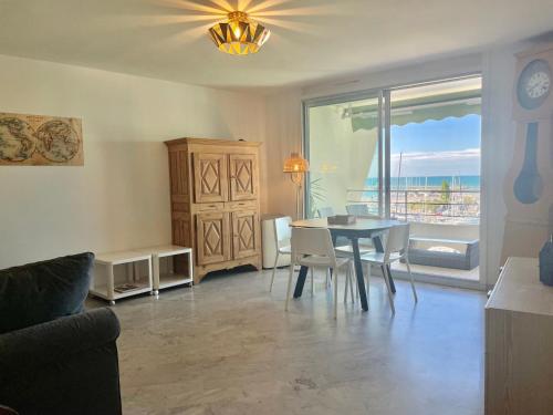 une salle à manger avec une table et des chaises et une fenêtre dans l'établissement PGH N34 - Vue Mer & Port, Climatisé, à La Grande Motte