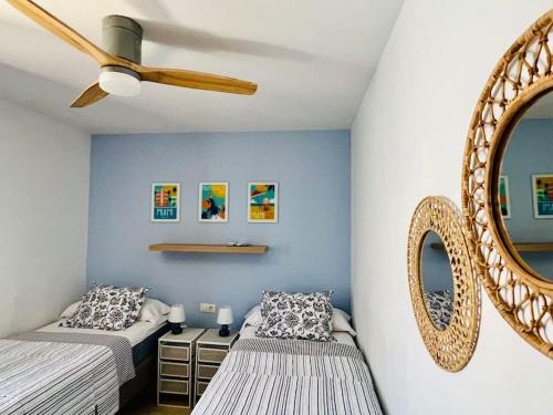 two beds in a room with a mirror and a ceiling fan at Lovely Villa Danielle in Playa Blanca