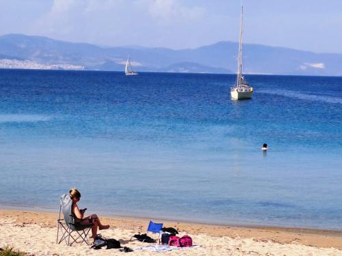 a woman sitting in a chair on the beach at SUN and Sea HOUSE Kavala ammolofoi αμμόλοφοι in Eleftheres