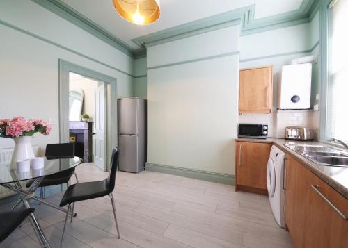 a kitchen with a table and a stainless steel refrigerator at Glebe Apartment 1 in Harrogate