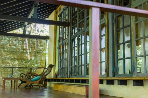 a room with a bench and a table and windows at Sama Retreats - Kosgoda in Kosgoda