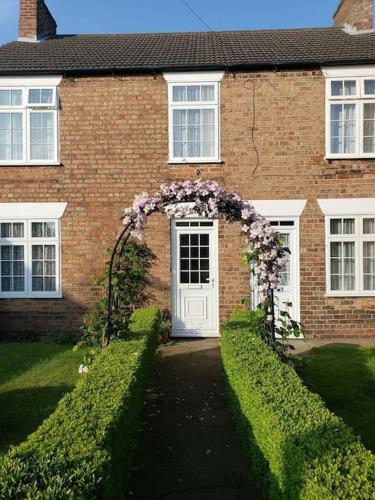 a brick house with an arch with flowers on it at Lavender Cottage, a pretty period cottage in Louth in Louth
