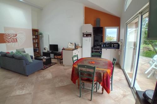 un salon avec une table et une cuisine dans l'établissement La Bananeraie La Bernerie en Retz, à La Bernerie-en-Retz
