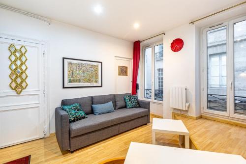 - un salon avec un canapé gris et quelques fenêtres dans l'établissement GuestReady - Quaint retreat in the heart of Paris, à Paris