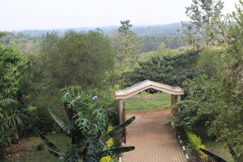 a bridge over a dirt road in a forest at Tinka,s Homestead in Fort Portal