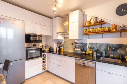 une grande cuisine avec des armoires et des appareils blancs dans l'établissement GuestReady - Contemporary Apt in the 20th Arr, à Paris